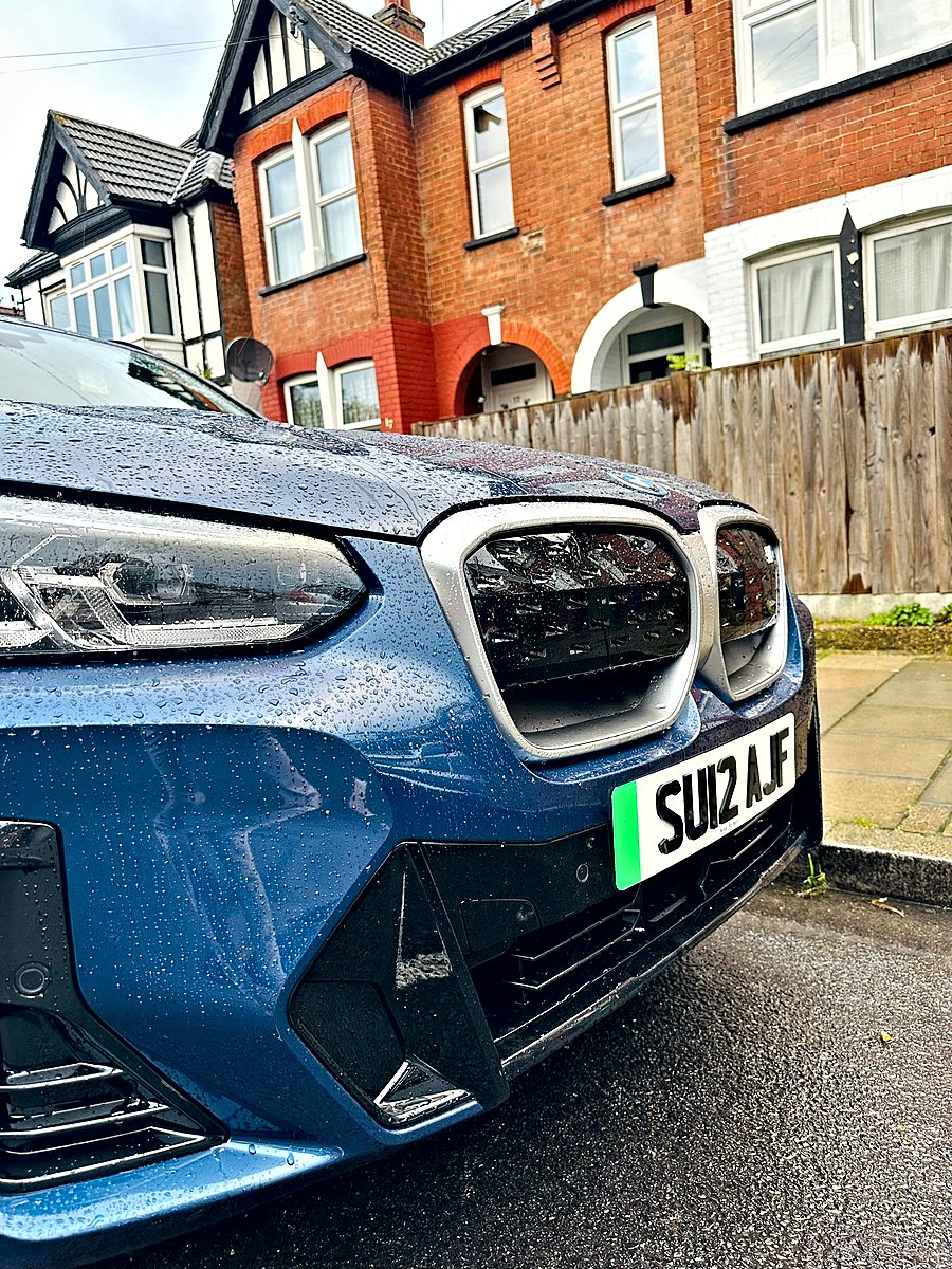 White front plate with a green flash on a blue electric BMW