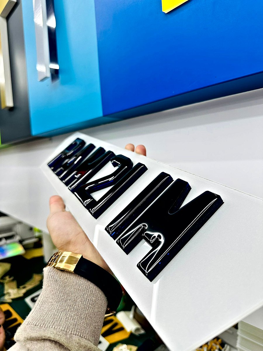 A hand holding a white plate with thick glossy gel letters