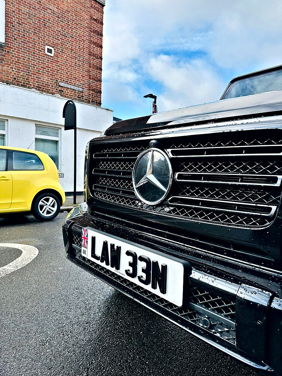 White front plate with a Union flag badge and raised letters on a black Mercedes G-Class