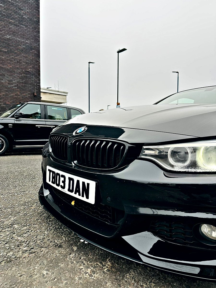 White front plate with raised black letters on a black BMW