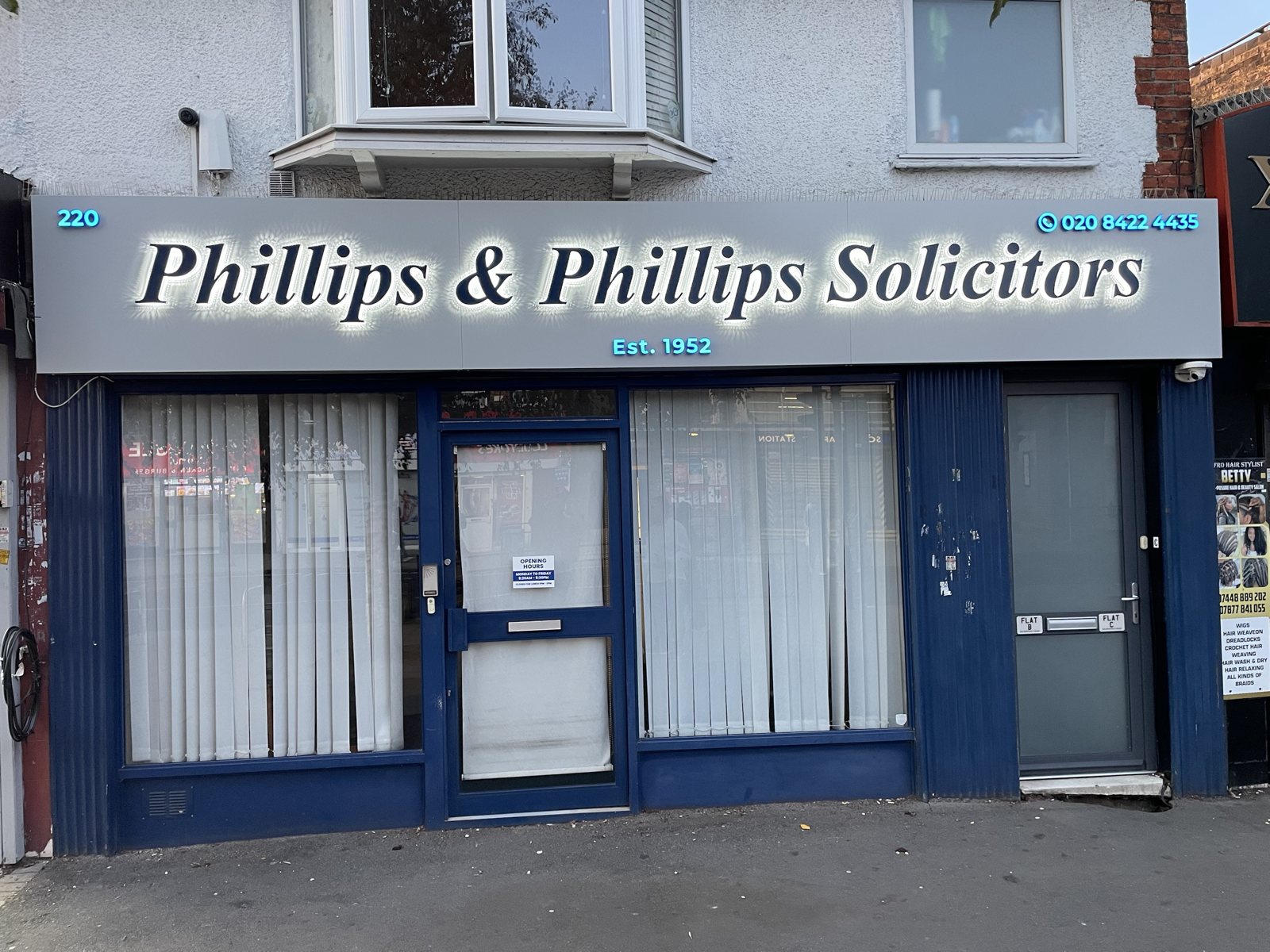 Phillips & Phillips Solicitors fascia with the lights on, letters glowing with a white halo