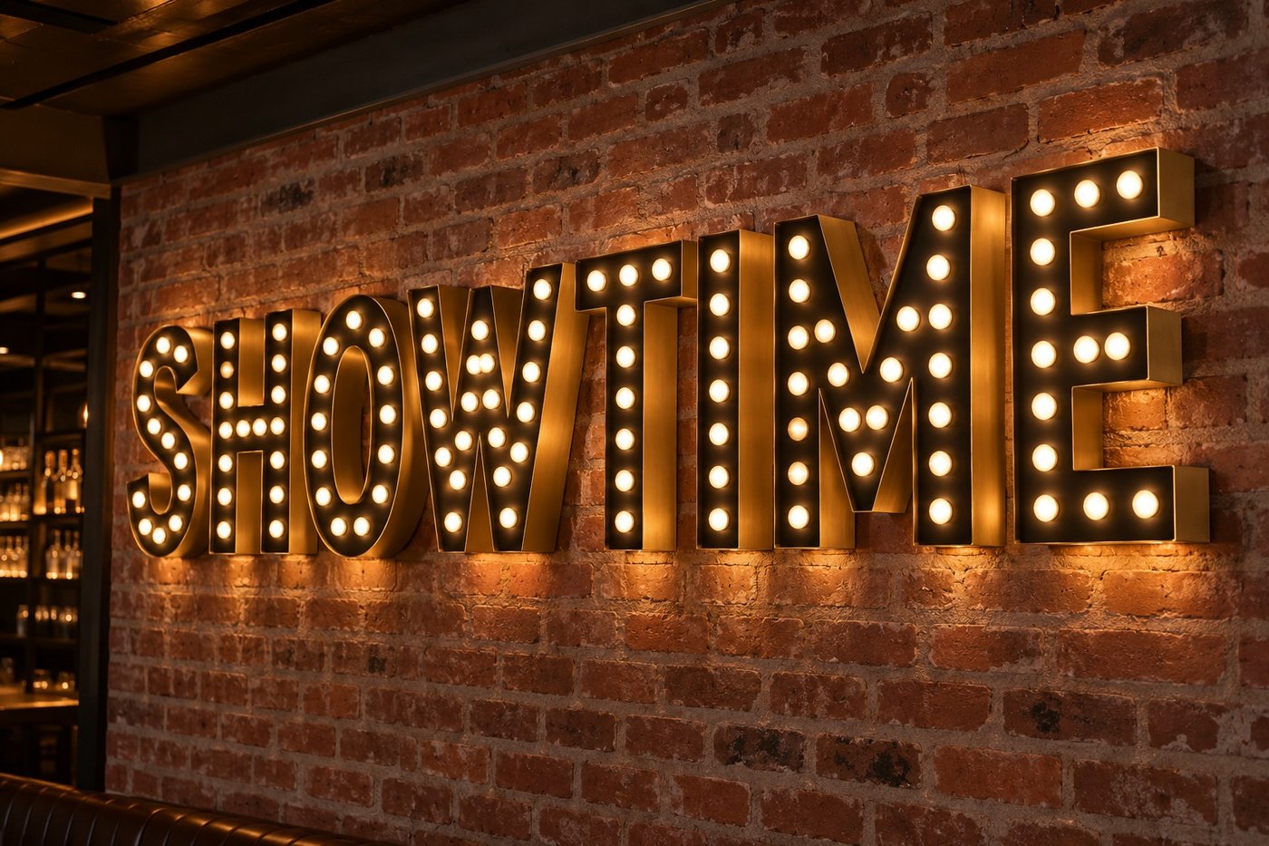 Brass and black letters filled with glowing bulbs reading SHOWTIME on a brick wall