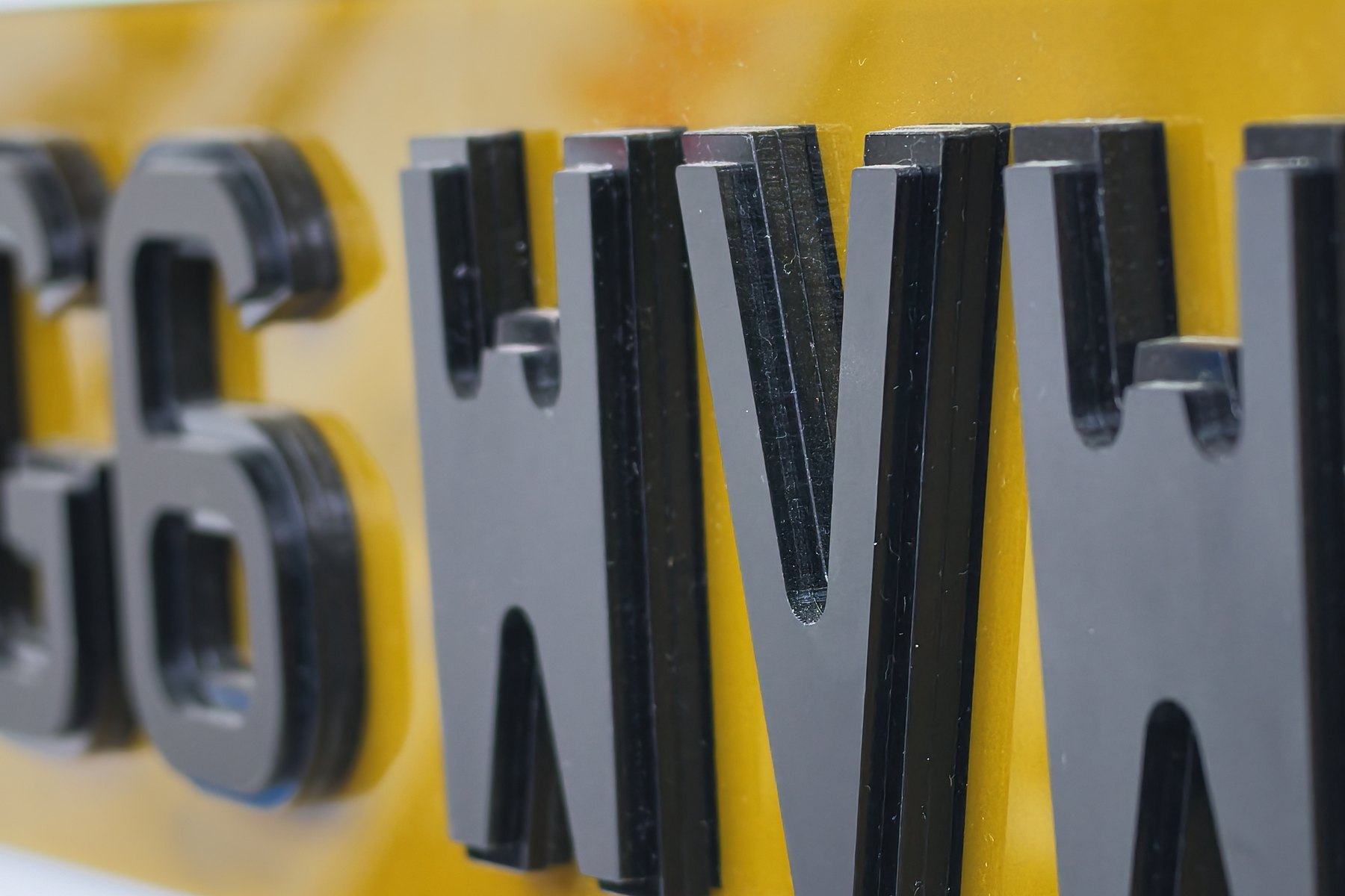 Close-up of raised 4D laser-cut letters on a yellow number plate